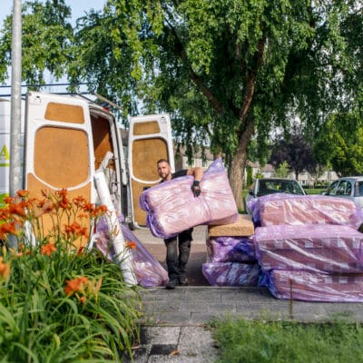 Medewerkers isolatiebedrijf tillen isolatiemateriaal vanuit de werkbus